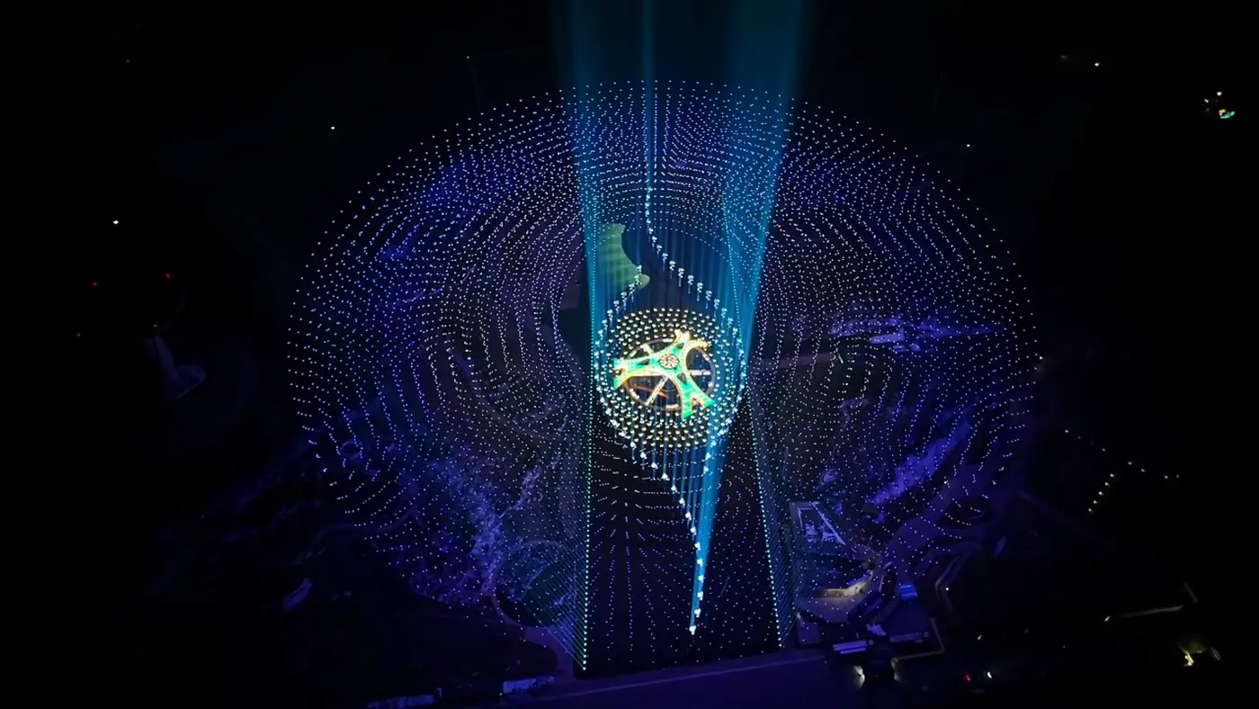 Cúpula de drones luminosos con figura ornamental dorada en el centro durante un festival nocturno